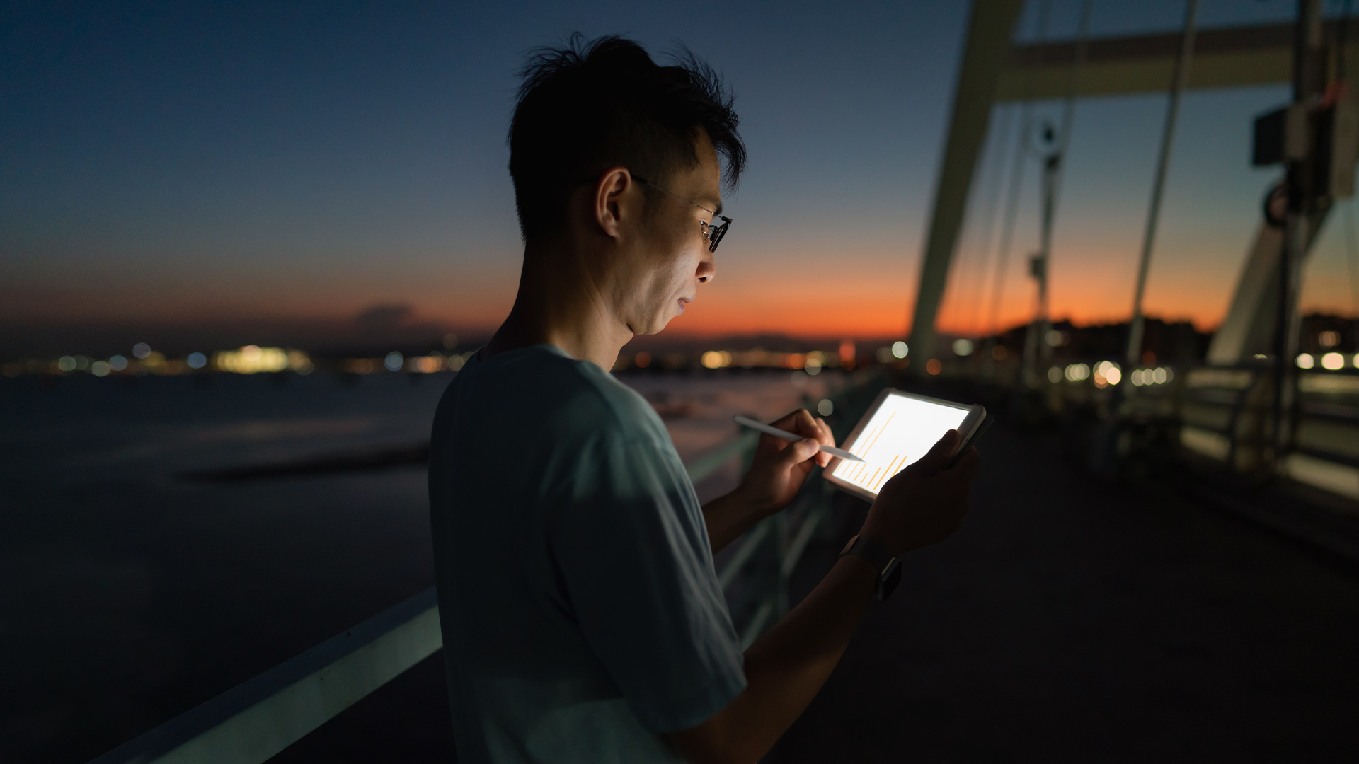 A man works with a tablet in the background you can see a sunset.